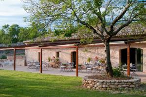 un patio con mesas, sillas y un árbol en Borgo Della Marmotta en Spoleto