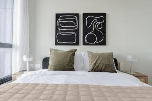 a bedroom with a white bed with two pictures on the wall at Blueground at Tzameret, Spacious, Balcony in Tel Aviv