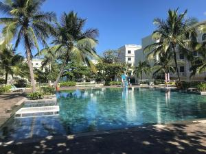 a large swimming pool with palm trees in front of a building at My Marina Beach Hotel Phu Quoc in Phú Quốc