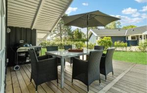 a table with chairs and an umbrella on a deck at Three-Bedroom Holiday Home In Sydals in Skovbyballe