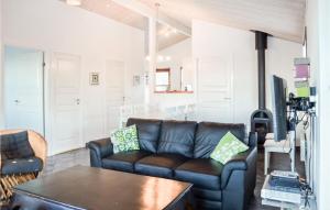 a living room with a leather couch and a table at Holiday Home Hellesvej Vestervig Denm in Vestervig