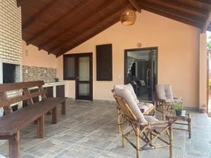 a patio with a wooden bench and chairs on it at Villa A with Sea View in Garopaba