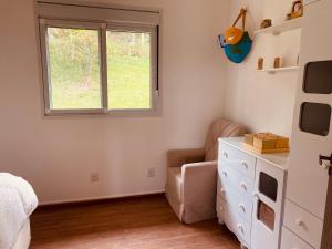 a bedroom with a bed and a dresser and a window at Villa A with Sea View in Garopaba