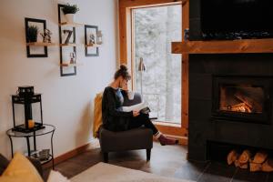 eine Frau auf einem Stuhl in einem Wohnzimmer mit Kamin in der Unterkunft Zazz - For precious moments with family or friends in Chertsey