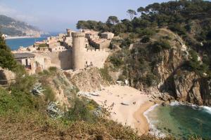 a beach in front of a castle on a mountain at Apartamento grande a 3min playa in Tossa de Mar