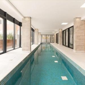 a large swimming pool with a green tile floor and windows at 1306 - Luxuoso Studio BF - CWB Central - Com Garagem in Curitiba