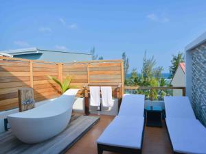 a balcony with a tub and chairs on a deck at Coconut Tree Hulhuvilla Beach in Hulhumale