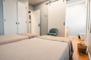 2 camas en una habitación con silla verde en Stone House, en Achadinha