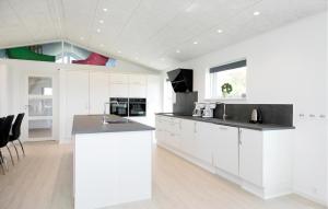a kitchen with white cabinets and black counter tops at Awesome Home In Jerup With Kitchen in Bratten Strand