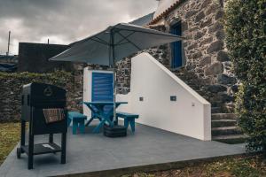 un patio con una mesa y una sombrilla en Stone House, en Achadinha