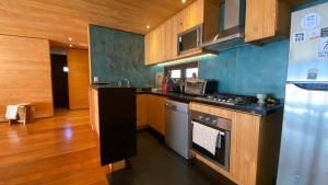eine Küche mit Holzschränken und einem Herd mit Backofen in der Unterkunft Casa Morro Punta de Lobos in Pichilemu
