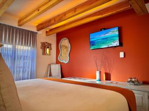 a bedroom with an orange wall with a flat screen tv at Hotel Boutique Casa Laja in San Miguel de Allende