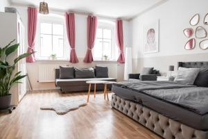 a bedroom with a bed and a couch and windows at SchaeBu! 1 Ferienwohnung im Herzen von Cottbus in Cottbus