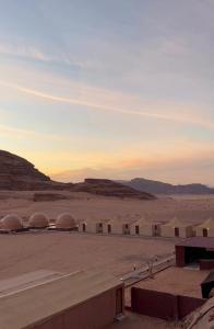 a group of domes in the desert at sunset at Camille WadiRum Camp in Disah