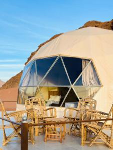 a tent with chairs and a table in the desert at Camille WadiRum Camp in Disah