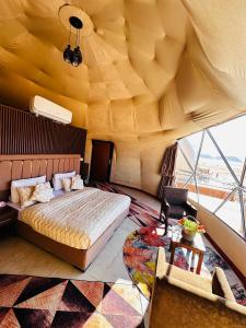 a bedroom with a large bed and a large window at Camille WadiRum Camp in Disah
