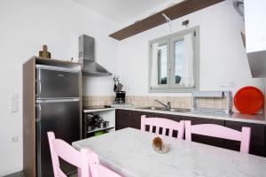 a kitchen with pink chairs and a table and a refrigerator at Maison a la Plage in Faros