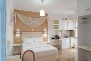 a bedroom with a white bed and a small kitchen at Aggelos Studios in Adamantas
