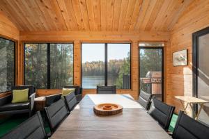 a dining room with a table and chairs and windows at Le Plein Sud - Your ideal getaway by Lake Lise in Chertsey