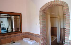 a bathroom with a sink and a mirror and a tub at Casa Rural Peña Falcón in Torrejón el Rubio