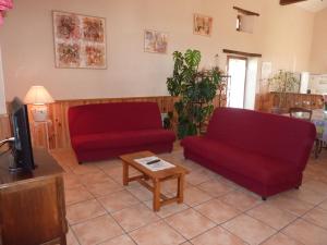 ein Wohnzimmer mit zwei roten Sofas und einem TV in der Unterkunft Gîte de l'Ivronnière in La Ronde
