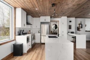 eine Küche mit weißen Geräten und einer Holzdecke in der Unterkunft O Sommet -Game room-Spa-sauna-Lake Access in Chertsey