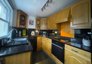 a kitchen with wooden cabinets and a black dishwasher at Byways in Keswick