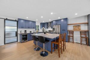 a kitchen with blue cabinets and a kitchen island with bar stools at Flora's House in Calgary +15 photos