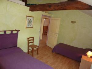 ein Schlafzimmer mit einem lila Bett und einem Stuhl in der Unterkunft Gîte de l'Ivronnière in La Ronde
