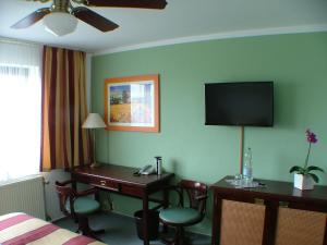 a hotel room with a desk and a television on the wall at Hotel garni Pension Zur Lutherstadt in Lutherstadt Eisleben