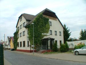 Hotel garni Pension Zur Lutherstadt في لوثرستادت ايسليبن: بيت ابيض كبير فيه ايفي ينمو عليه