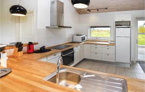 a kitchen with white cabinets and a sink at Holiday Home Pilemose in Skovby