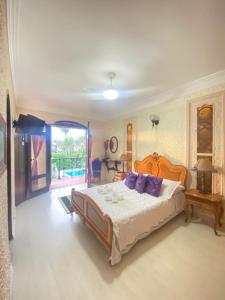 a bedroom with a large bed with purple pillows at Pousada Chez Moi in Cabo Frio