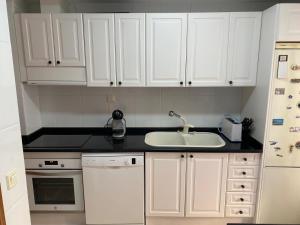 a kitchen with white cabinets and a sink at Apartamento Marisol in Alcañiz