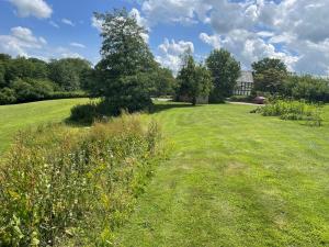 a field of grass with a house in the background at The Coach House in Tilston