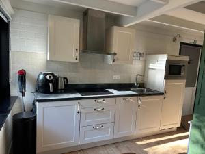 a kitchen with white cabinets and a sink and a refrigerator at Vakantiehuis Lanaken in Lanaken +16 photos