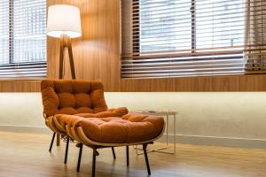 a brown leather chair sitting in a room with a lamp at TW Cyclinn Vila Olimpia in São Paulo