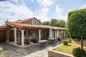a house with a patio with a table and chairs at Casa Rural Dona María in Ordes