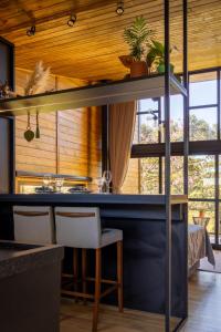 a kitchen with a counter with chairs and a table at Vivenda das Araucárias 02 Microcasa Aconchegante lareira, banheira in Rio Rufino
