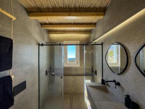 a bathroom with a shower and a sink and a mirror at Perigiali Rooms & Apartments Folegandros in Agali