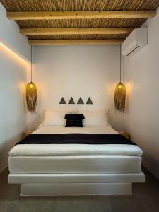 a bedroom with a white bed with two lights at Perigiali Rooms & Apartments Folegandros in Agali