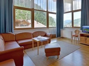 a living room with a couch and large windows at Ferienwohnungen Haus der Mitte in Mayrhofen