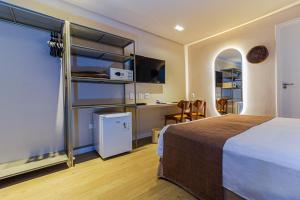 a hotel room with a bed and a desk and a kitchen at Littoral Express in João Pessoa