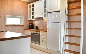 a kitchen with white cabinets and a refrigerator at Frk Lyng in Harboør +15 photos
