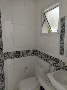 une salle de bain avec toilettes, lavabo et fenêtre dans l'établissement Casa Barra do Una Sol, Mar e Cahoeiras, à São Sebastião