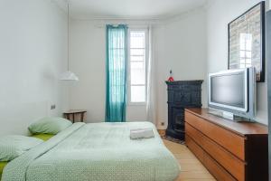a bedroom with a bed and a television on a dresser at Beautiful family flat nearby the Flea Market, Stade de France, Montmartre in Saint-Ouen