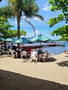 people sitting at tables on a beach with umbrellas at Refugio Bela Ilha Luxo Casal Acesso por Barco in Florianópolis