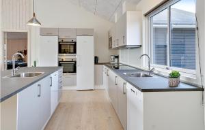 a kitchen with white cabinets and stainless steel appliances at Nice Home In Ålbæk With Kitchen in Ålbæk