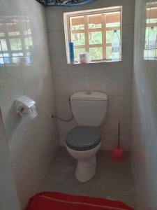 a bathroom with a toilet with a window and a red rug at Villa de la Plage sous les cocotiers in Saly Portudal +2 photos