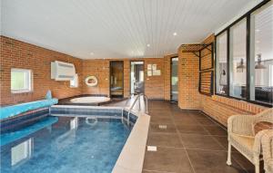 a house with a swimming pool and a brick wall at Cozy Home In Asperup With Sauna in Asperup